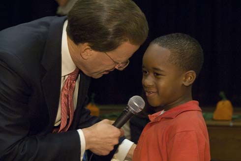 Joseph A. Craig Elementary School Milken Family Foundation Chairman Lowell Milken gets some help from a young Craig Elementary volunteer as he makes an important announcement.