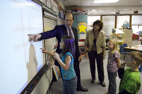 Empire Elementary School Milken Institute Chairman Michael Milken helps teach a lesson on the Smart Board as new Milken Educator Gayle Magee and some of her students watch.