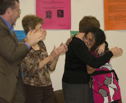 Horace Mann Dual Language Magnet School Colleagues applaud and another gives a congratulatory hug to Vanessa Martinez, surprise recipient of a $25,000 Milken Educator Award.