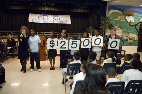 Rock Chapel Elementary School Students from Rock Chapel Elementary hold up cards displaying the amount of the Milken Educator Award, which Dr. Jane Foley is about to present to one of their teachers.
