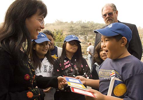 Solano Avenue Elementary School Joni Milken-Noah, a Milken Family Foundation trustee and vice president of Mike's Math Club, delights a young Solano Avenue Elementary student with a fun math game as Solano Avenue Elementary Principal Richard Hickcox looks on.