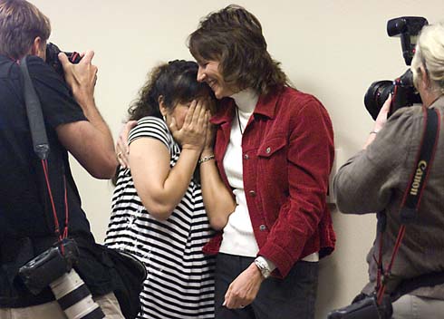 Valley Elementary School Marissa Ochoa shyly hides her face after being surprised with a $25,000 Milken Educator Award as a colleague gives her a congratulatory hug and photographers snap photos of her reaction.