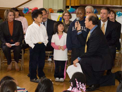Visitacion Valley Elementary School Mike Milken (right, with microphone), co-founder of the Milken Family Foundation, asks a young Visitacion Valley student to define 'excellence.'  The student replies, 'It's better than 'good' and 'great.'' Dignitaries seated behind the students include House Speaker Nancy Pelosi (left), San Francisco Unified School District Superintendent Carlos Garcia (fourth from left) and California Superintendent of Public Instruction Jack O'Connell (second from right).