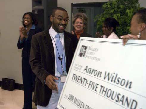 F. B. Woodley Elementary School Fifth-grade teacher Aaron Wilson steps forward to accept an oversized check representing his $25,000 Milken Educator Award.